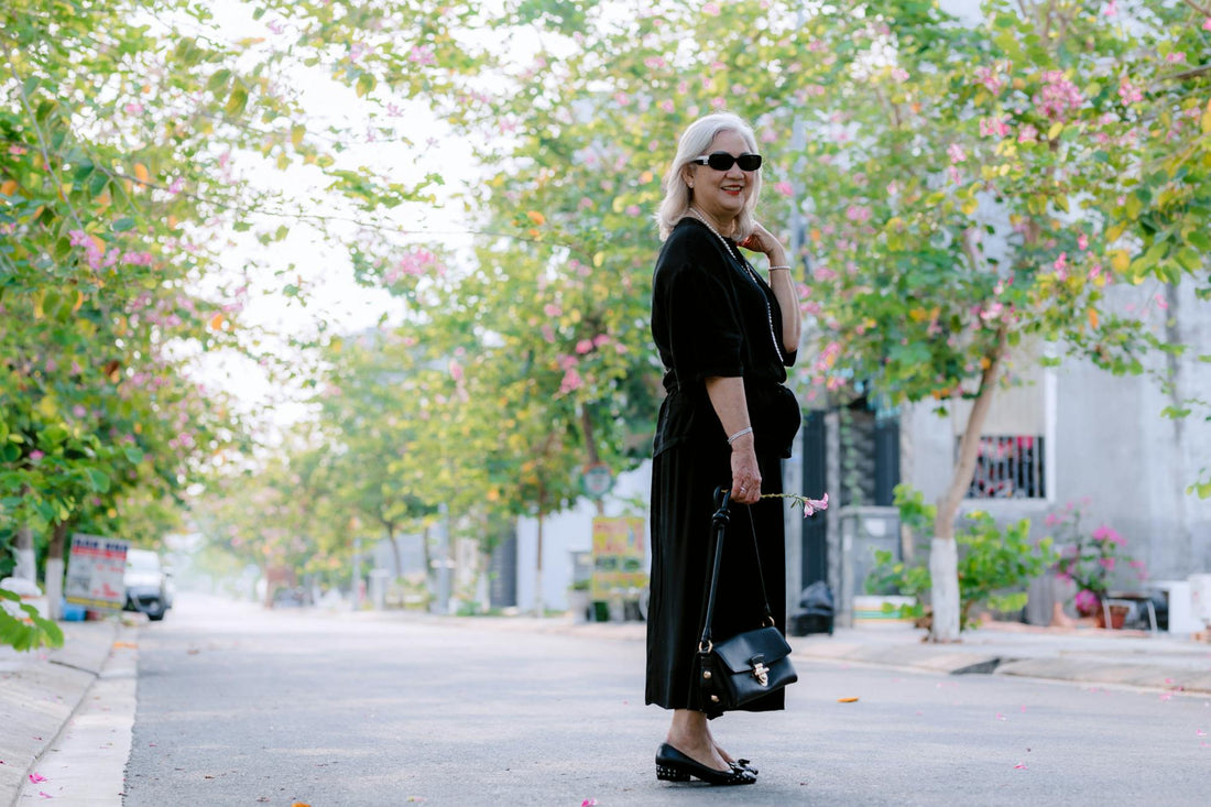 Elegant senior woman in sunglasses walking on a sunlit street