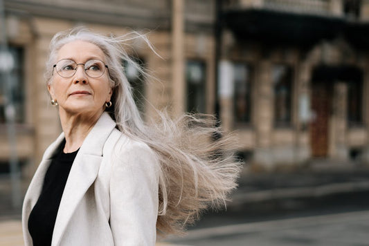 Older woman with natural silver hair smiling — purple shampoo vs blue shampoo for grey hair
